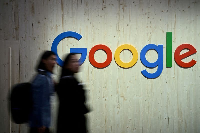 Foto de Archivo: Personas caminan junto al logo de Google, durante una fería comercial en Hannover, Alemania