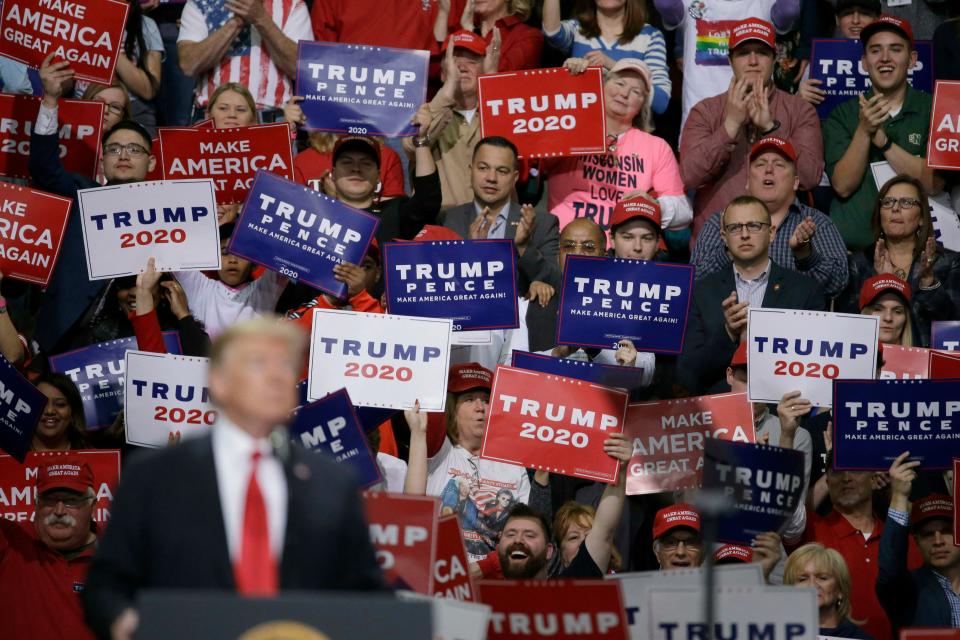 President Donald Trump speaks at a Make America Great Again rally as supporters hold up signs, April 27, 2019, in Green Bay, Wisconsin.