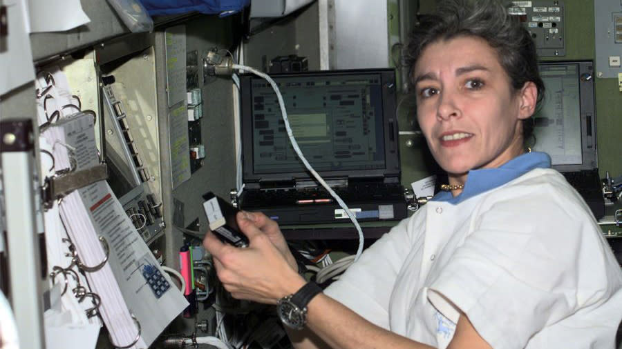 Claudie Haigneré looks at the camera while attending to an experiment while in space.