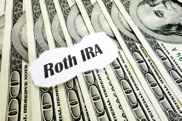 A piece of paper that reads "Roth IRA" on top of a fanned out pile of cash.