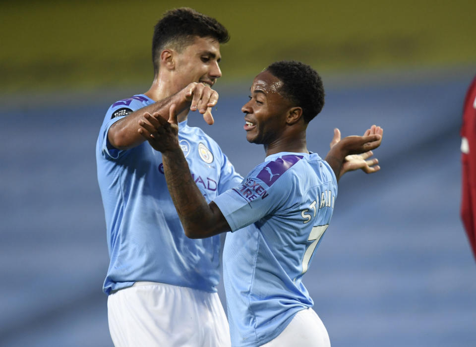 Raheem Sterling, del Manchester City, es felicitado por su compañero Rodrigo, durante la victoria sobre el Liverpool en la Liga Premier, el jueves 2 de julio de 2020 (AP Foto/Peter Powell,Pool)