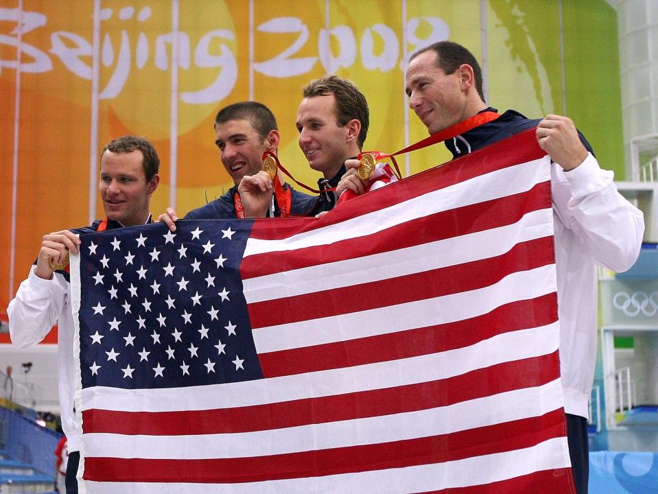 American swimmers hold up the American flag after winning gold in the 4x100 relay at the 2008 Olympics..
