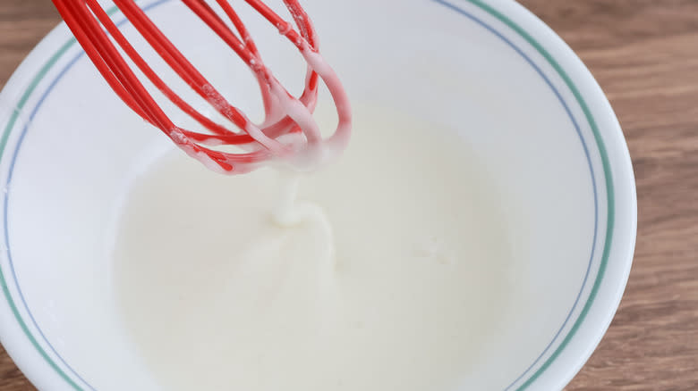 white liquid in white bowl with rubber whisk