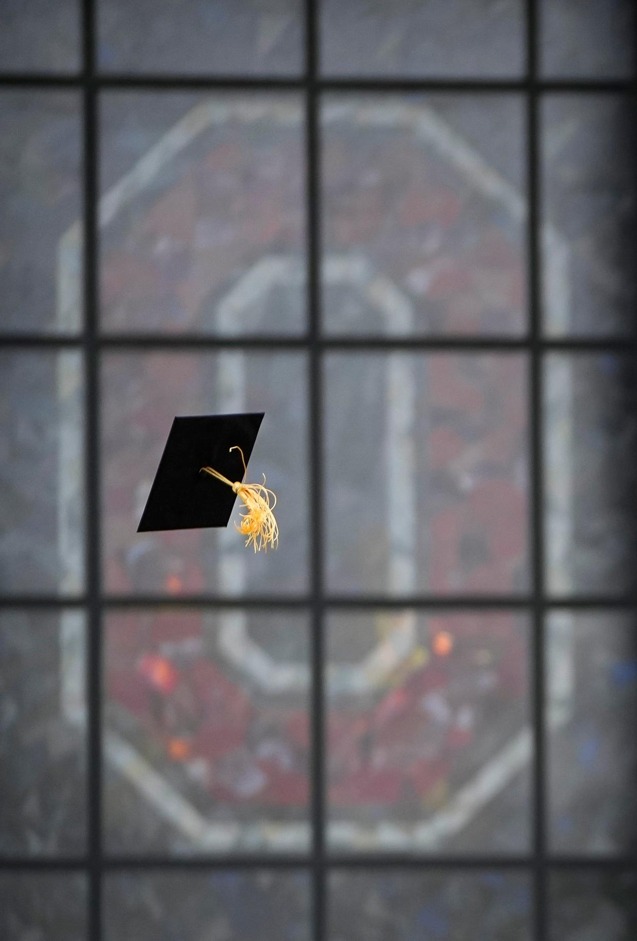 A soon-to-be graduate tosses their cap in the air while taking photos under the Ohio Stadium rotunda in their graduation regalia on May 4, 2022. Ohio State's spring commencement is inside the stadium on Sunday, May 8.