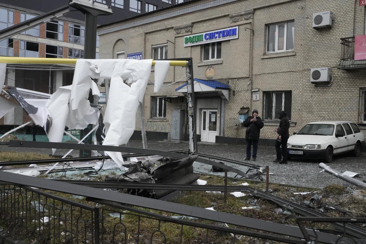 A woman takes a photo of the consequences of Russian shelling in Kyiv, Ukraine, Thursday, Feb. 24, 2022. (AP Photo/Efrem Lukatsky)