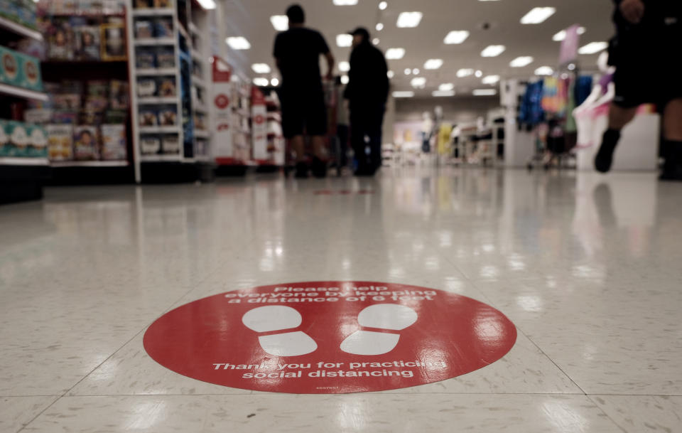 To protect from the coronavirus a social distancing spot is painted on the floor while shoppers wait in line at a Target store in the Van Nuys section of Los Angeles on Friday, April 24, 2020. (AP Photo/Richard Vogel)