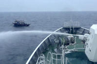 In this late May, 2019, image from video provided by Japan Coast Guard, Japan Coast Guard patrol boat sprays water to a North Korean fishing boat after the fishing boat didn't ignore the warning to evacuate in the waters near Yamatotai, Japan. Japanese Coast Guard says its patrol boats have been pushing back hundreds of North Korean poachers swarming toward fishing grounds off Japan’s northern coast.(Japan Coast Guard via AP)