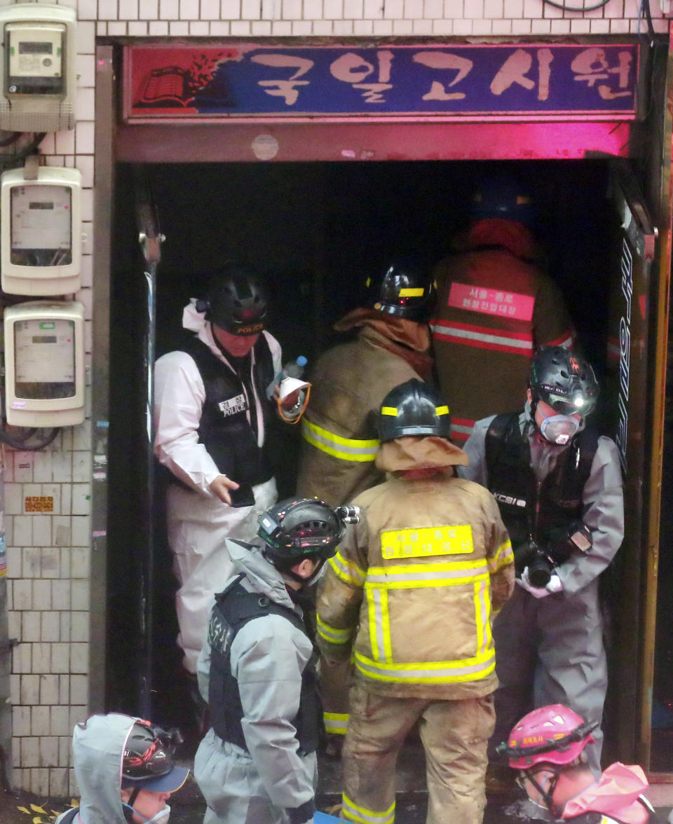 South Korean firefighters and police officers work at the gate of a fire site in Seoul, South Korea, Friday, Nov. 9, 2018. A fire at a low-cost dormitory-style housing facility in central Seoul killed several people on Friday, fire authorities said. (Hong Hae-in/Yonhap via AP)