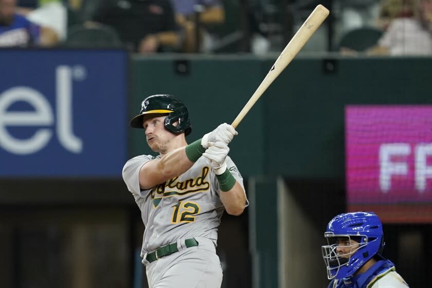 Sean Murphy, de los Atléticos de Oakland, conecta un dole delante del colombiano Meibrys Viloria, cátcher de los Rangers de Texas, el miércoles 17 de agosto de 2022 (AP Foto/Tony Gutiérrez)