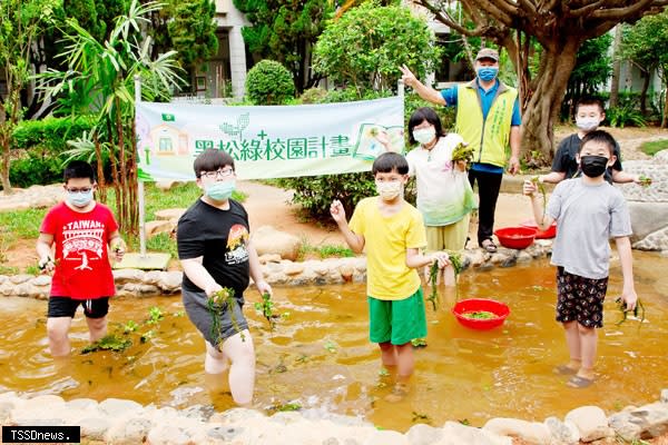 霄裡國小師生體驗校園埤塘的水生植物種植，右三為台灣濕地復育協會吳聲譽老師，右四為霄裡國小古艷麗校長。（圖：黑松教育基金會提供）