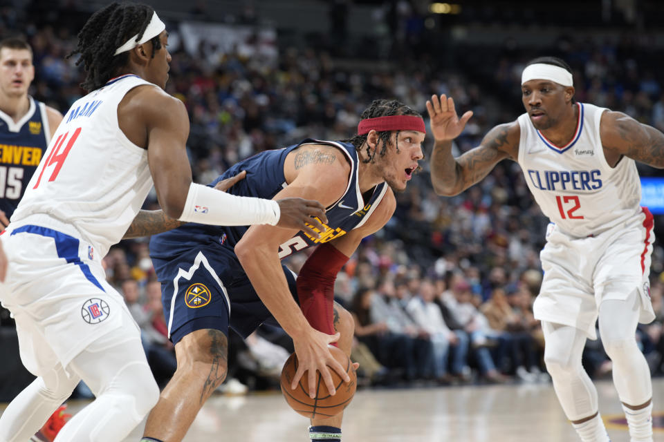 Denver Nuggets forward Aaron Gordon, center, is trapped with the ball between Los Angeles Clippers guards Terance Mann, left, and Eric Bledsoe in the first half of an NBA basketball game Wednesday, Jan. 19, 2022, in Denver. (AP Photo/David Zalubowski)