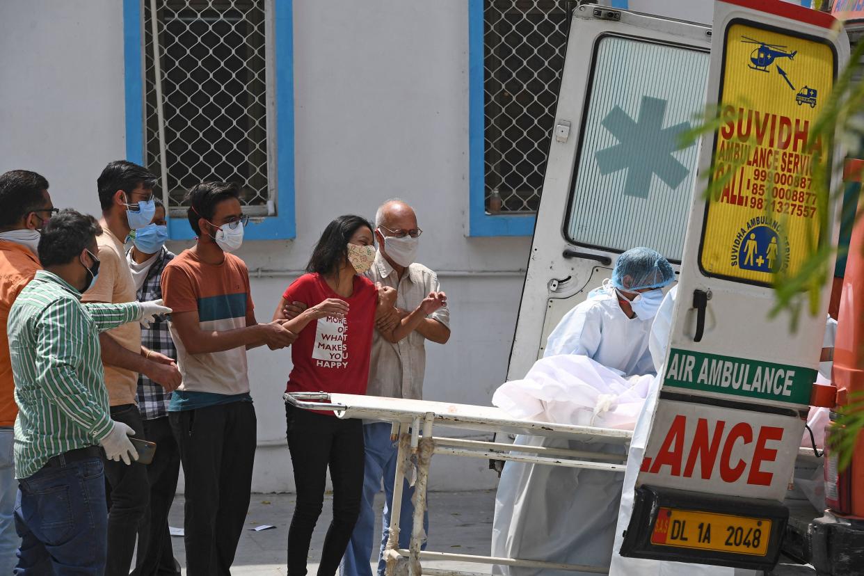 People try to console a woman mourning for the demise of her relative who died of Covid-19 coronavirus as the body is being transferred into an ambulance at a mortuary in New Delhi on April 29, 2021.