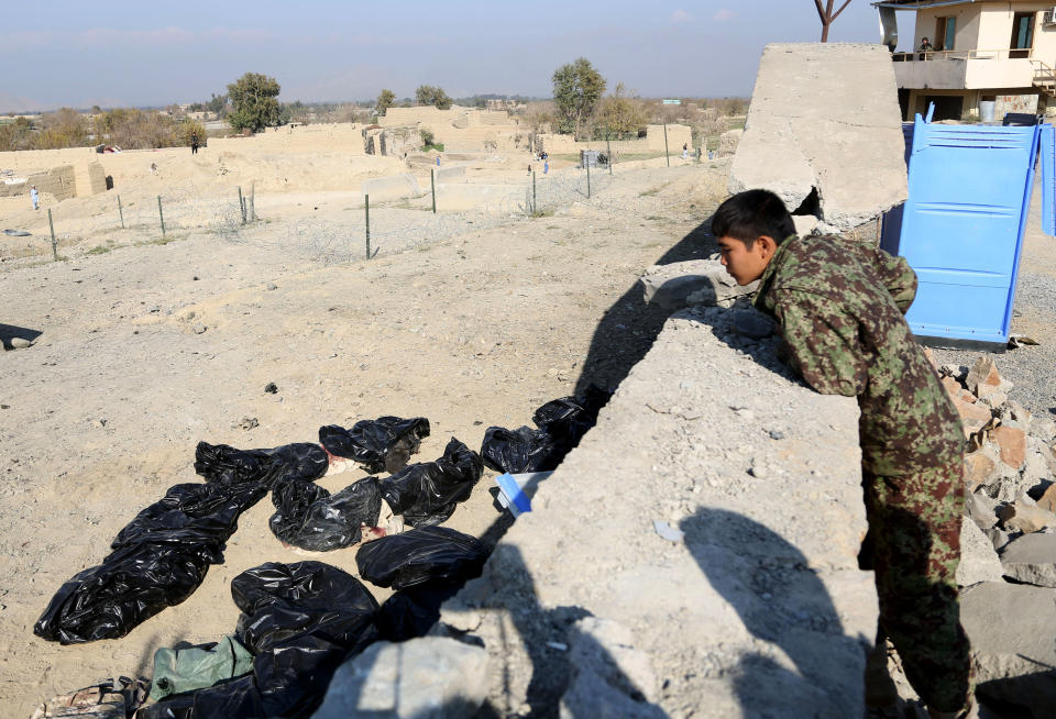 A member of the Afghan national army investigating the site of a deadly suicide attack on a joint NATO-Afghan base look at body bags in Nangarhar province, east of Jalalabad, Afghanistan, Saturday, Jan. 4, 2014. NATO said a service member died following a suicide bombing in eastern Afghanistan, without identifying the soldier's nationality. An official said five Taliban fighters on foot tried to storm the base after the bombing, but Afghan and NATO troops returned fire, killing the attackers. (AP Photo/Rahmat Gul)