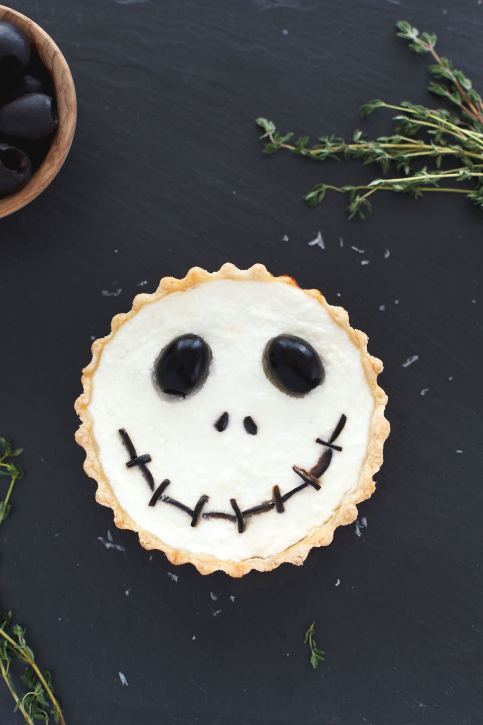 <p>Add extra olive accents on the outside of this cheesy tomato tart to pay homage to Mr. Halloween himself.</p><p>Get the <strong><a href="https://www.snixykitchen.com/halloween-jack-skellington-ricotta-olive-tarts/" rel="nofollow noopener" target="_blank" data-ylk="slk:Jack Skellington Ricotta Olive Tart recipe;elm:context_link;itc:0;sec:content-canvas" class="link ">Jack Skellington Ricotta Olive Tart recipe</a></strong> from Snixy Kitchen. </p>