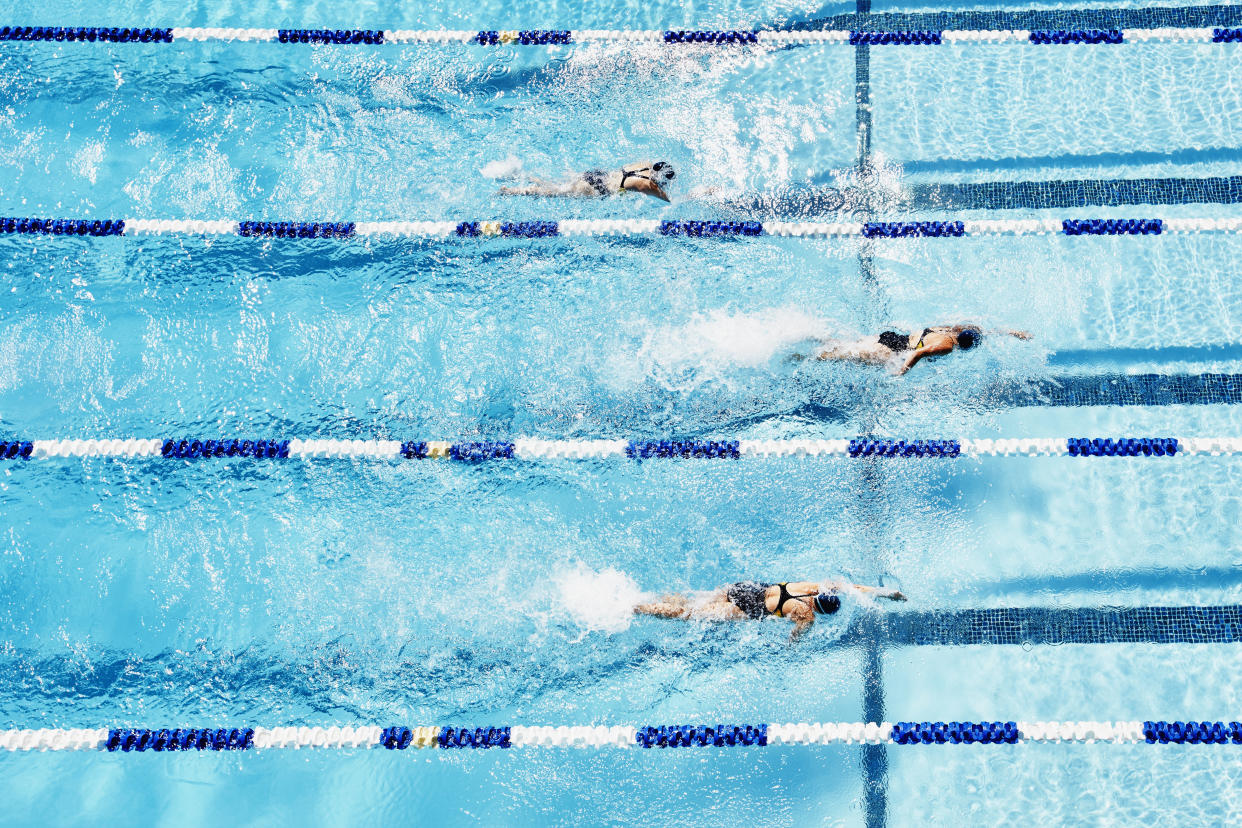 Young female competitive swimmers racing in outdoor pool overhead view