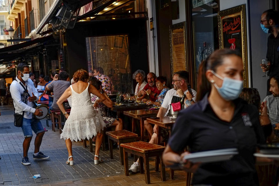 People enjoy a summer's day, in Benidorm, south-east Spain, Saturday, June 26, 2021. Almost a year after face masks became mandatory indoors and outdoors in Spain, people from Saturday are no longer required to wear them outside as long as they can stay at least 1.5 meters (5 feet) apart. (AP Photo/Alvaro Barrientos)