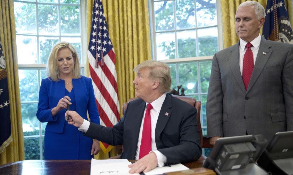 Donald Trump signs the executive order to end family separations while watched by the DHS secretary, Kirstjen Nielsen, and the vice president, Mike Pence.