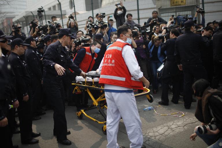 Chinese paramedics assist a person who fainted as relatives of passengers on the missing Malaysia Airlines flight MH370 protest outside the Malaysian embassy in Beijing, on March 25, 2014