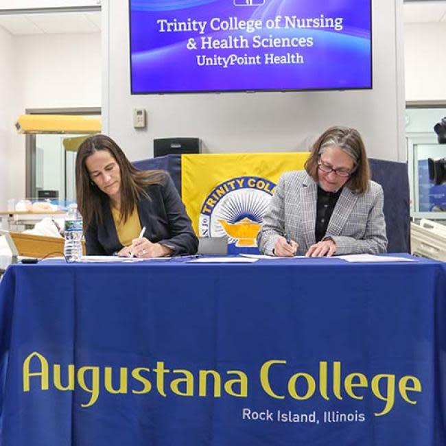 Augustana president Andrea Talentino, left, and Trinity College chancellor Tracy Poelvoorde sign the new agreement.