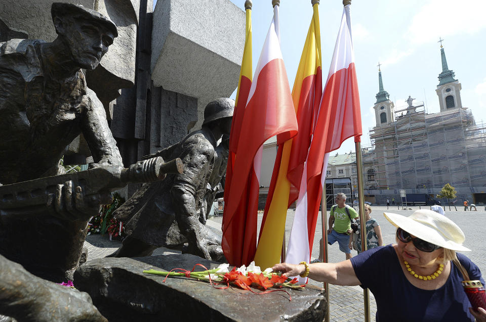 Warsaw residents lay flowers at the monument to the 1944 Warsaw Rising against the occupying Nazis to honor some 18,000 resistance fighters who fell in the struggle against the German forces and some 180,000 civilians who perished 74 years ago, in Warsaw, Poland, Wednesday, Aug. 1, 2018.(AP Photo/Czarek Sokolowski)