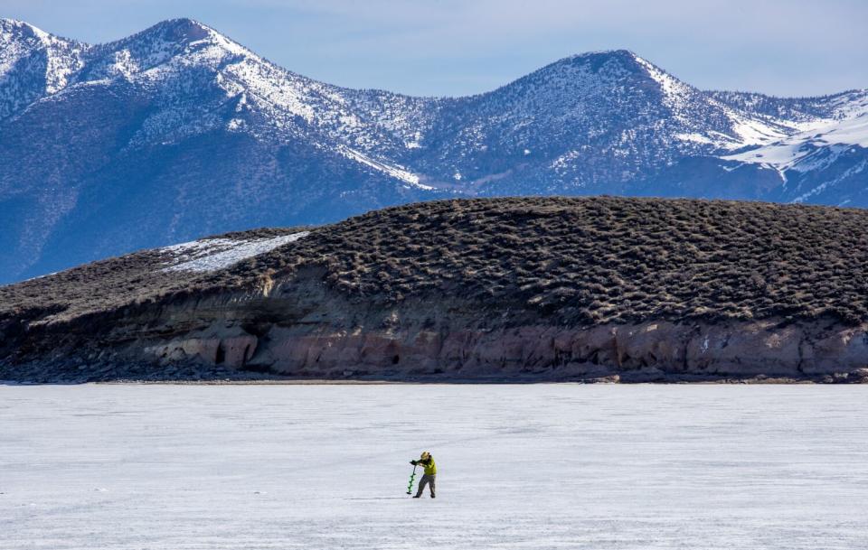 A fisherman augers in on a frozen Crowley Lake the official opening day of trout season.