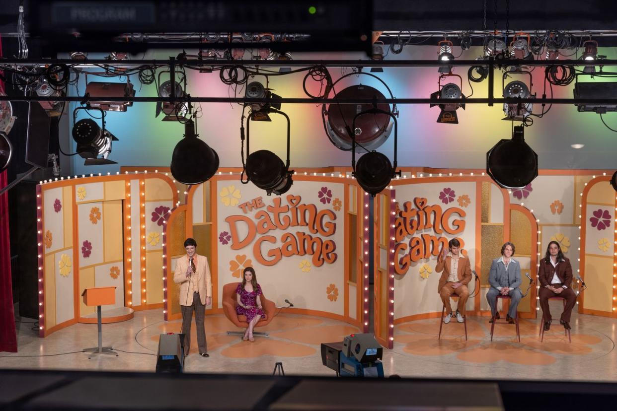 woman of the hour image, a 1970s tv studio called the dating game, with anna kendrick and tony hale on one side of a wall, and three men on stools on the other side