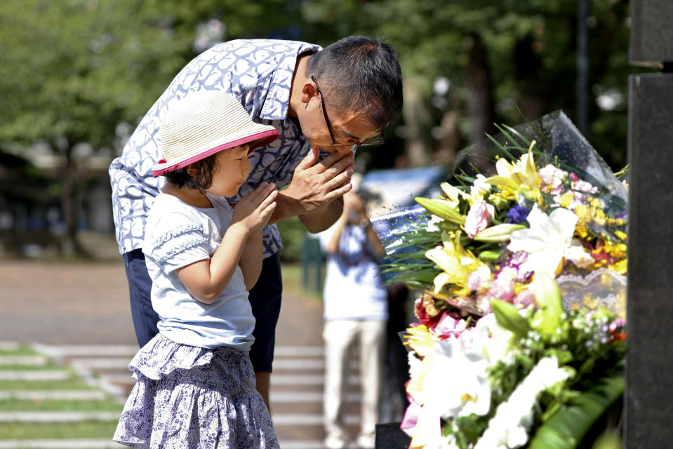 A man and his daughter pray for the victims of U.S. atomic bombing at the Atomic Bomb Hypocenter Park in Nagasaki, southern Japan, Sunday, Aug. 9, 2020. Nagasaki marked the 75th anniversary of the atomic bombing on Sunday. (Takuto Kaneko/Kyodo News via AP)