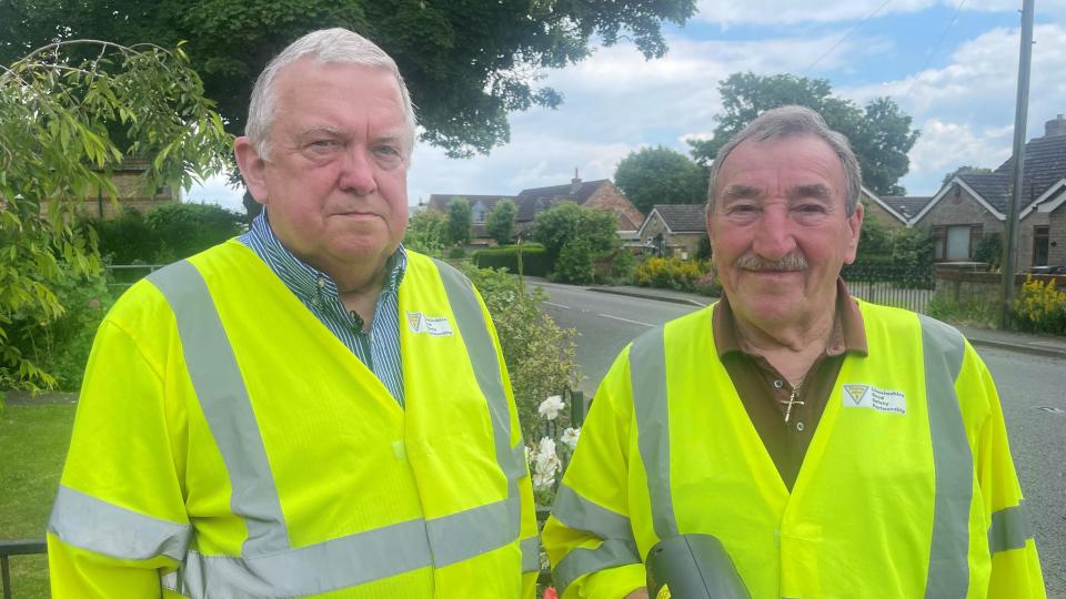 Two volunteers holding a speed gun