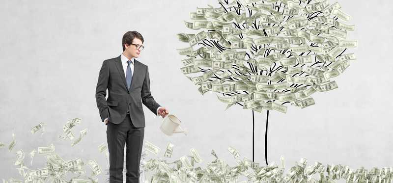 A man stands beside a tree growing money.
