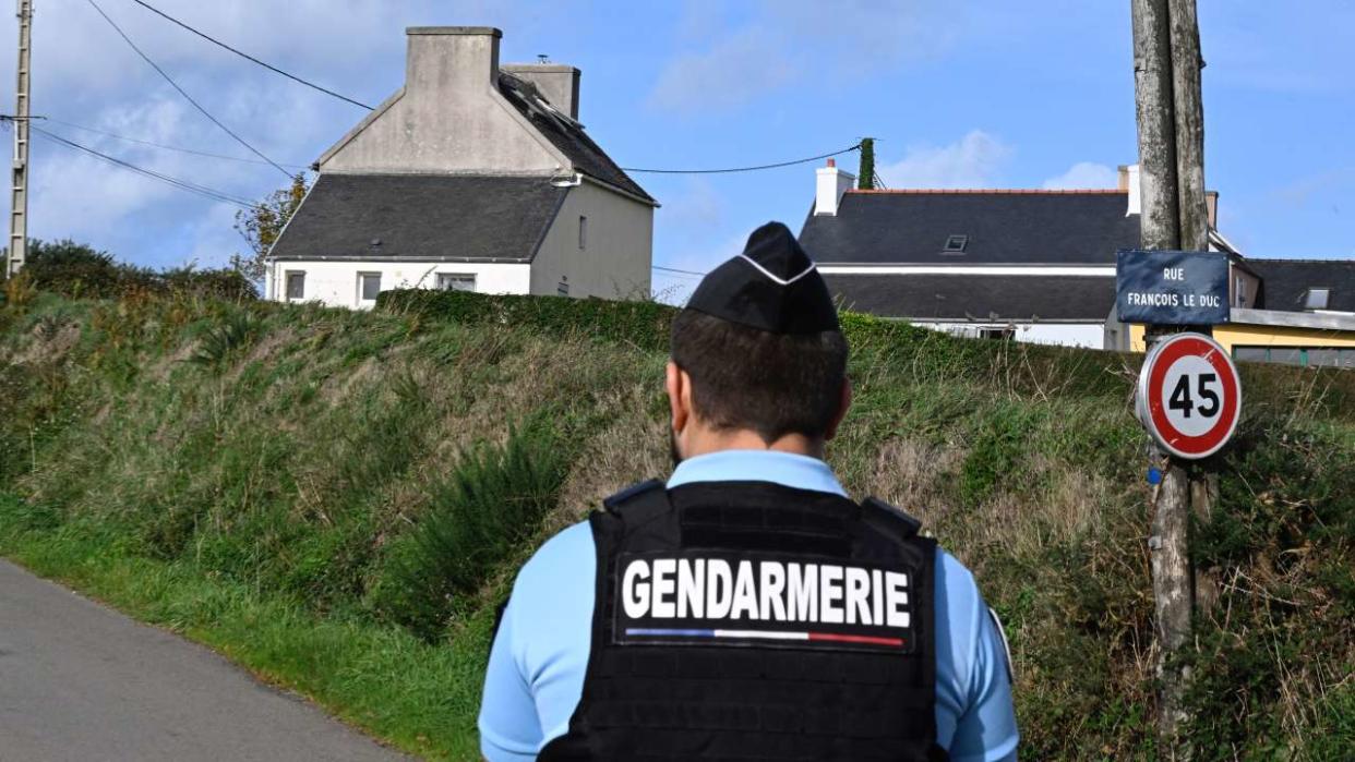 Un gendarme français monte la garde sur une route près d’une maison où quatre personnes ont été retrouvées mortes, à Carantec, dans l’ouest de la France, le 30 octobre 2022. - Un homme, une femme et deux jeunes filles d’une même famille ont été retrouvés morts le 30 octobre 2022 dans une maison à Carantec, près de Morlaix, dans l’ouest de la France. (Photo de DAMIEN MEYER / AFP)