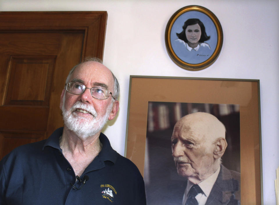 In this June 7, 2019 photo, Ryan Cooper stands next to a photo of Otto Frank, the father of the famed Holocaust victim and diarist Anne Frank, at his home in Yarmouth, Mass. Above the photo is a painting of Anne Frank by Cooper, a local artist who has donated a trove of letters and mementos he received from Otto Frank to the U.S. Holocaust Memorial Museum ahead of the 90th anniversary of Anne Frank's birthday. (AP Photo/Philip Marcelo)