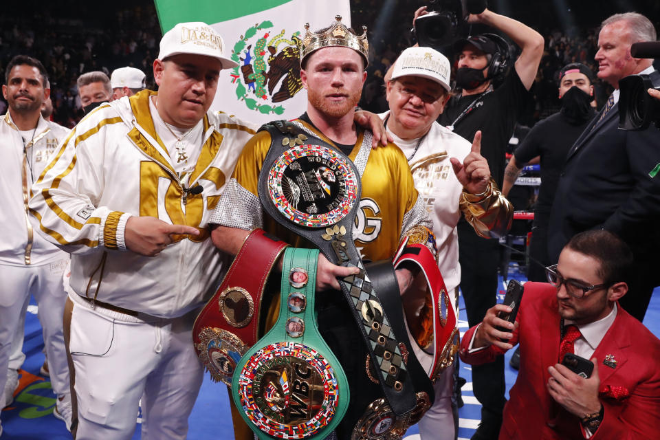 Canelo Alvarez, of Mexico, poses with the belts after defeating Caleb Plant in a super middleweight title unification fight Saturday, Nov. 6, 2021, in Las Vegas. (AP Photo/Steve Marcus)