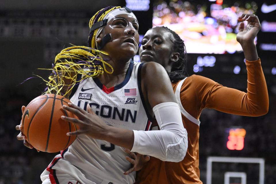 Connecticut's Aaliyah Edwards drives to the basket as Texas' Amina Muhammad, right, defends during the first half of an NCAA college basketball game, Monday, Nov. 14, 2022, in Storrs, Conn. (AP Photo/Jessica Hill)