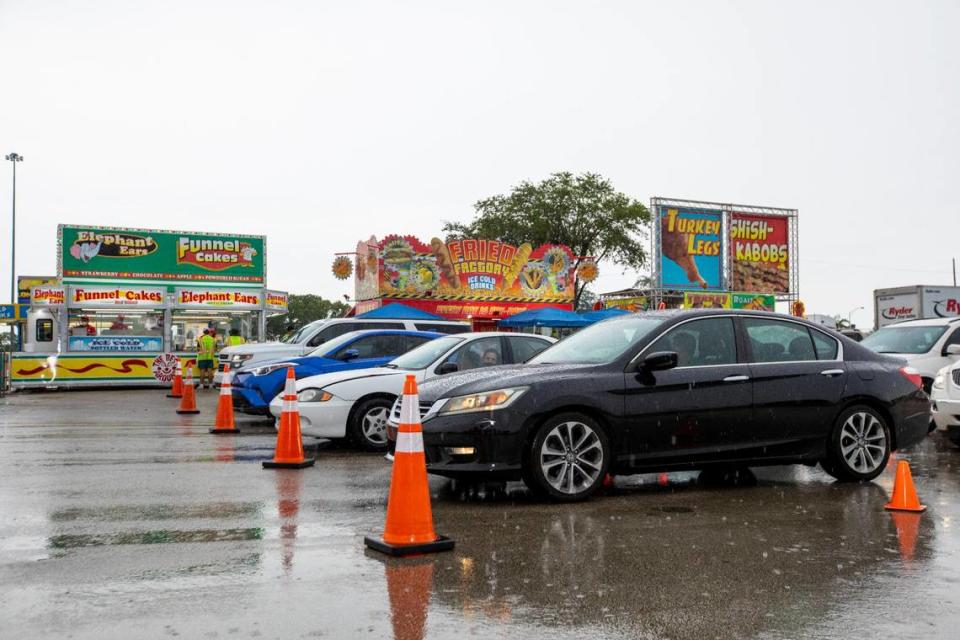 Food runners deliver orders to drivers as they wait in their cars in line during the Miami-Dade County Youth Fair food drive-through in Miami, Florida on Saturday, July 11, 2020.