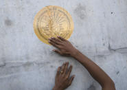 Pro-democracy protester Panupong Jadnok pastes a sticker of a plaque marking Thailand's transition to democracy on the wall of Parliament during a protest in Bangkok, Thailand, Thursday, Sept. 24, 2020. Lawmakers in Thailand are expected to vote Thursday on six proposed amendments to the constitution, as protesters supporting pro-democratic charter reforms gathered outside the parliament building. (AP Photo/Sakchai Lalit)