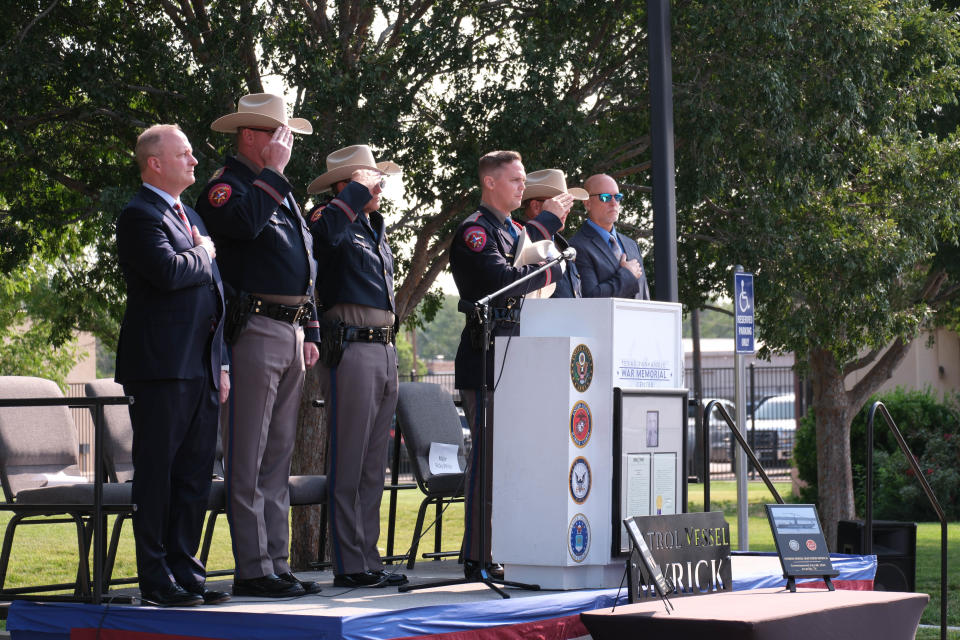 Members of DPS and State Rep. Four Price stand as the National Anthem is sung at a boat dedication ceremony for Trooper Matthew Myrick Friday morning at the Texas Panhandle War Memorial Center in Amarillo.