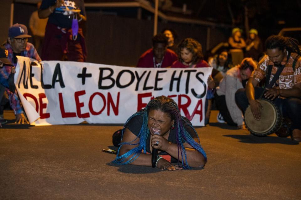 A woman speaks into a microphone while lying on the ground.