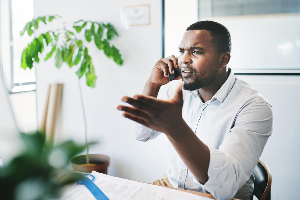 A man looking frustrated while talking on the phone