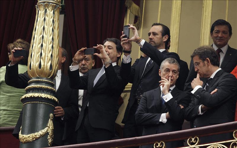 El lehendari, Iñigo Urkullu (2-d, primer termino), conversa con el presidente de la Xunta de Galicia, Alberto Núñez Feijóo (d), mientras que los presidentes autonómicos de Madrid, Ignacio González (i), y Baleares, José Ramón Bauzá, hacen fotografías con sus móviles durante el acto de proclamación ante las Cortes Generales del Rey Felipe VI. EFE