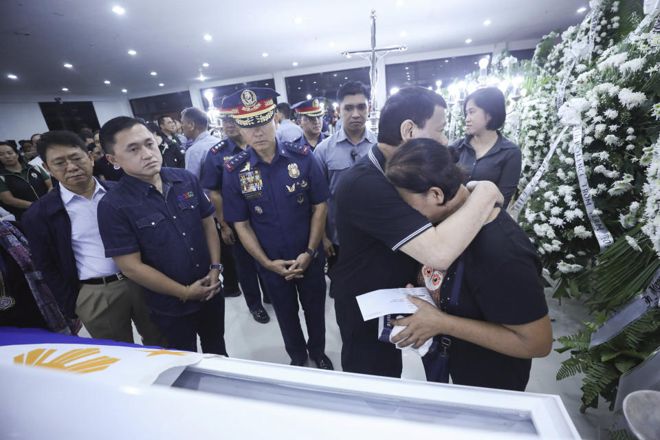 In this photo provided by the Presidential Malacanang Palace on Saturday July 20, 2019, Philippine President Rodrigo Duterte comforts relatives of slain police officers during his visit to their wake at Camp Lt. Col. Francisco C. Fernandez Jr. in Sibulan, Negros Oriental, in Central Philippines. On Thursday, July 25, 2019, President Rodrigo Duterte said he raised a reward of 3 million pesos ($59,000) out of anger for what he described as the Islamic State group-style killings of the officers on July 18 in Negros Oriental province. Communist guerrillas claimed responsibility for the attack but denied torturing the police officers. (Ace Morandante/Presidential Photo Via AP)