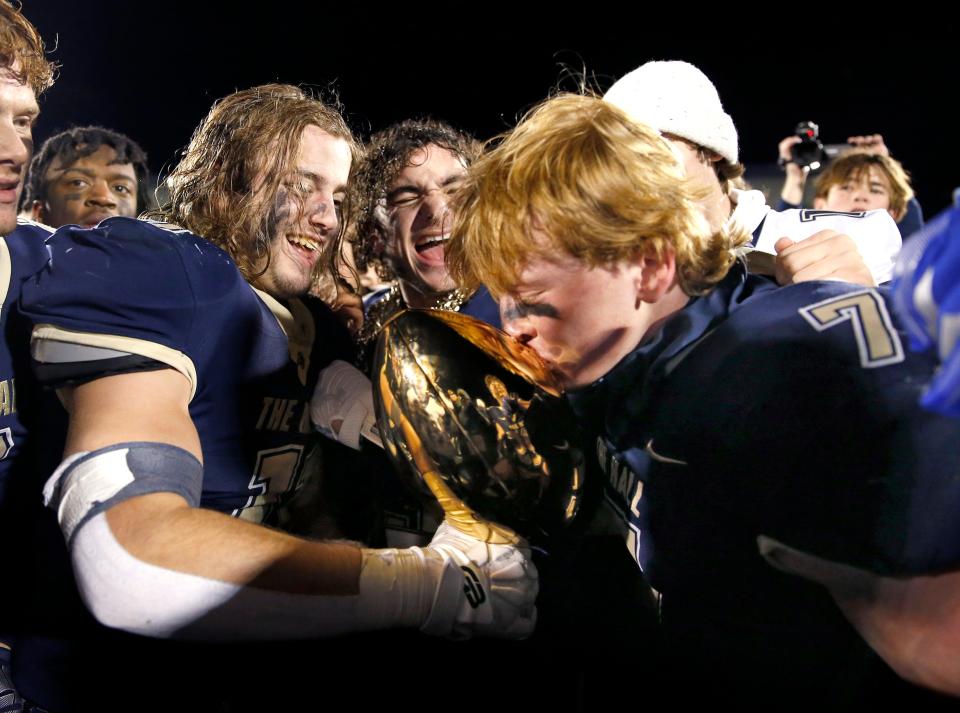 Heritage Hall's Andy Bass kisses the championship trophy after winning the Class 3A football title last season.