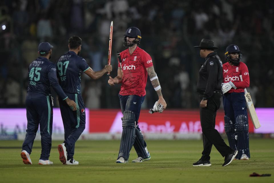 England's Reece Topley, center, and Adil Rashid, walk off the field as Pakistani players celebrate after winning the fourth twenty20 cricket match against England, in Karachi, Pakistan, Sunday, Sept. 25, 2022. (AP Photo/Anjum Naveed)