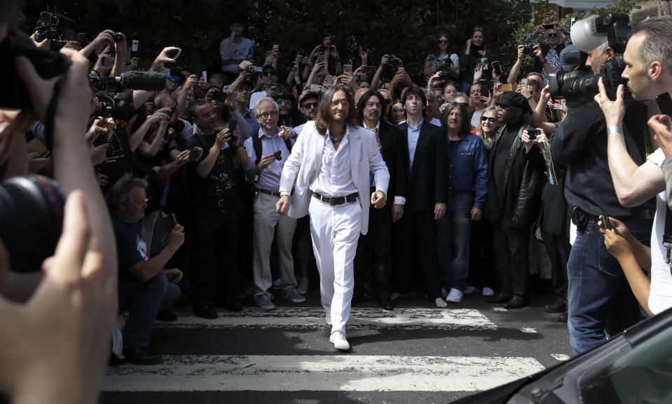 Thousands of fans gather to walk across the Abbey Road zebra crossing, on the 50th anniversary of British pop musicians The Beatles doing it for the cover of their album 'Abbey Road' in St Johns Wood in London, Thursday, Aug. 8, 2019. They aimed to cross 50 years to the minute since the 'Fab Four' were photographed for the album. (AP Photo/Kirsty Wigglesworth)