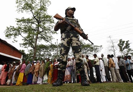 A security personnel stands guard as people line up to cast their vote outside a polling station in Nakhrai village in Tinsukia district in the northeastern Indian state of Assam April 7, 2014. REUTERS/Rupak De Chowdhuri
