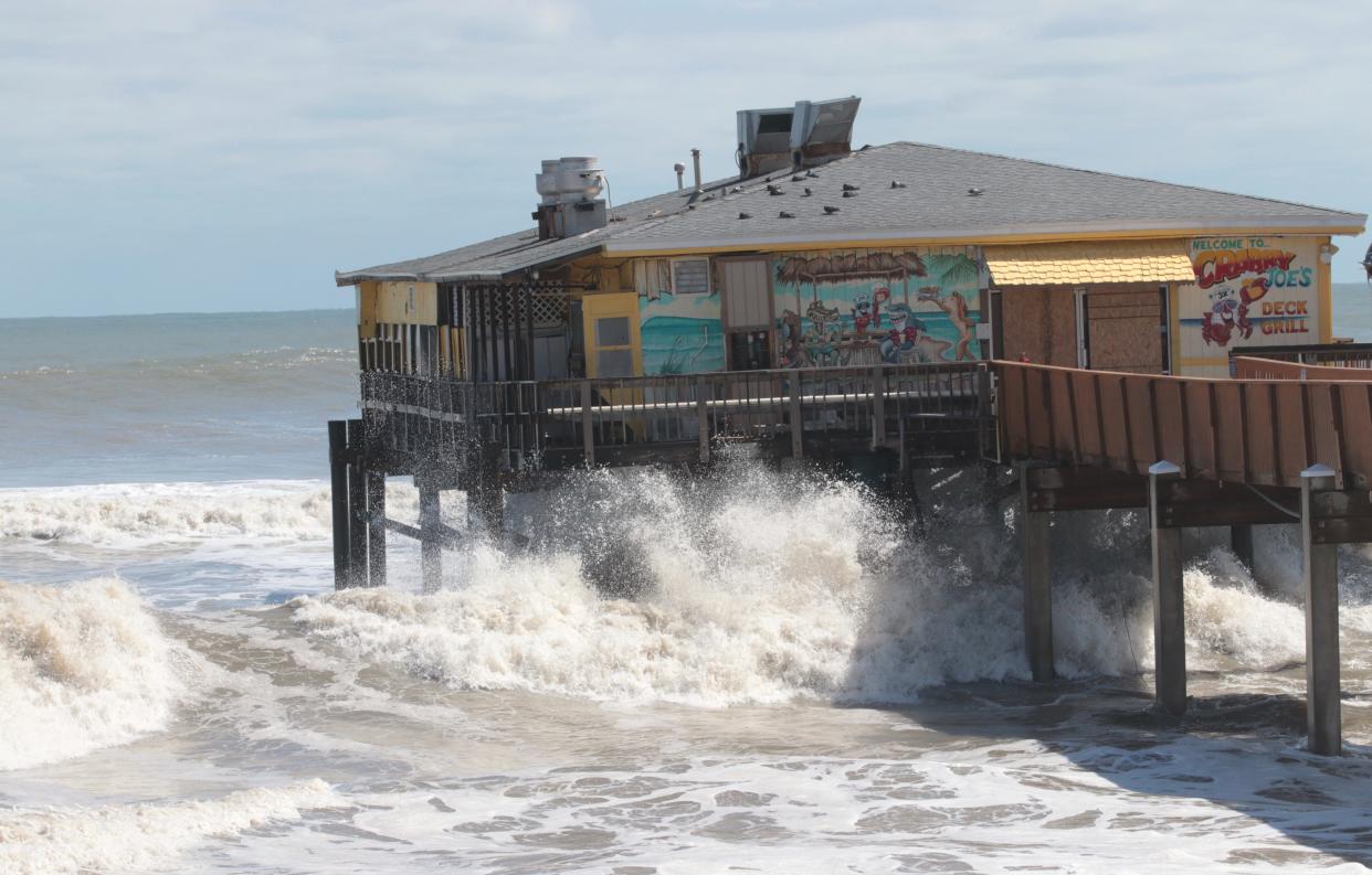 Waves crash against the posts of the Sunglow Pier and Crabby Joe's Deck & Grill restaurant in Daytona Beach Shores on Friday, Sept. 30, 2022. A portion of the iconic privately owned pier was sheared off during Tropical Storm Ian on Thursday. Its owners say they intend to rebuild the local landmark that opened in 1960.