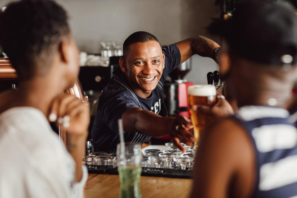 a bartender handing a drink over