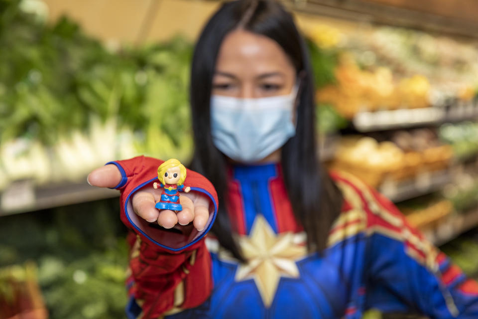A woman dressed as Captain Marvel, holding a Captain Marvel Ooshie, which Woolworths shoppers will be able to collect across Australia