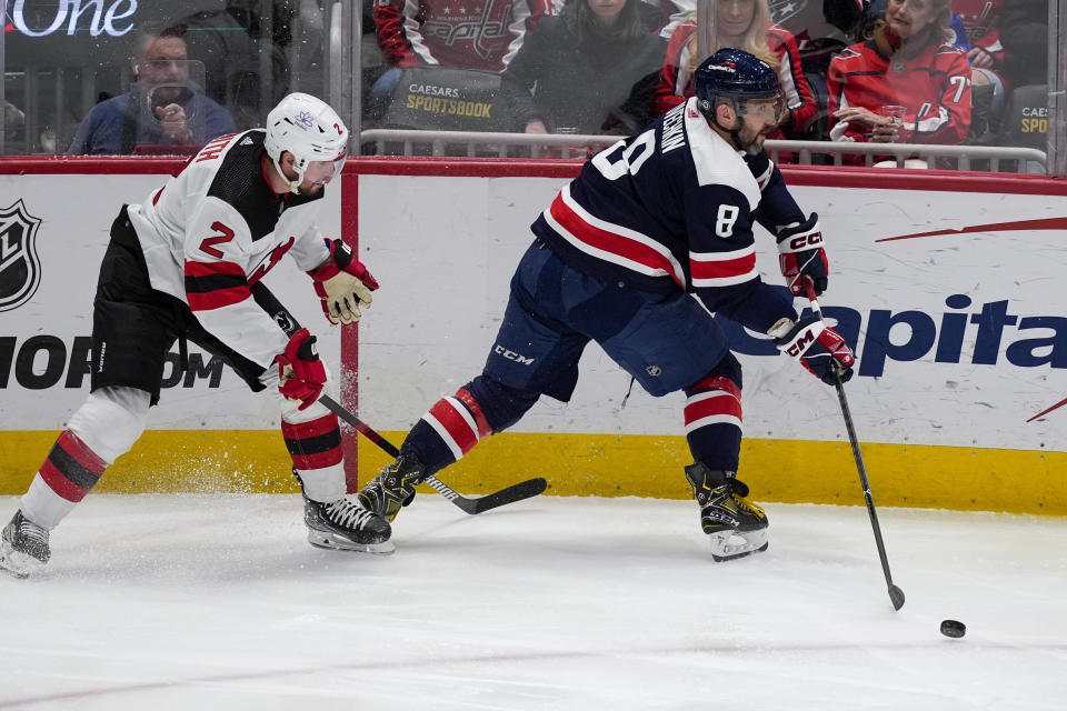 Washington Capitals left wing Alex Ovechkin (8) passes the puck with New Jersey Devils defenseman Brendan Smith (2) nearby during the third period of an NHL hockey game, Tuesday, Feb. 20, 2024, in Washington. (AP Photo/Alex Brandon)