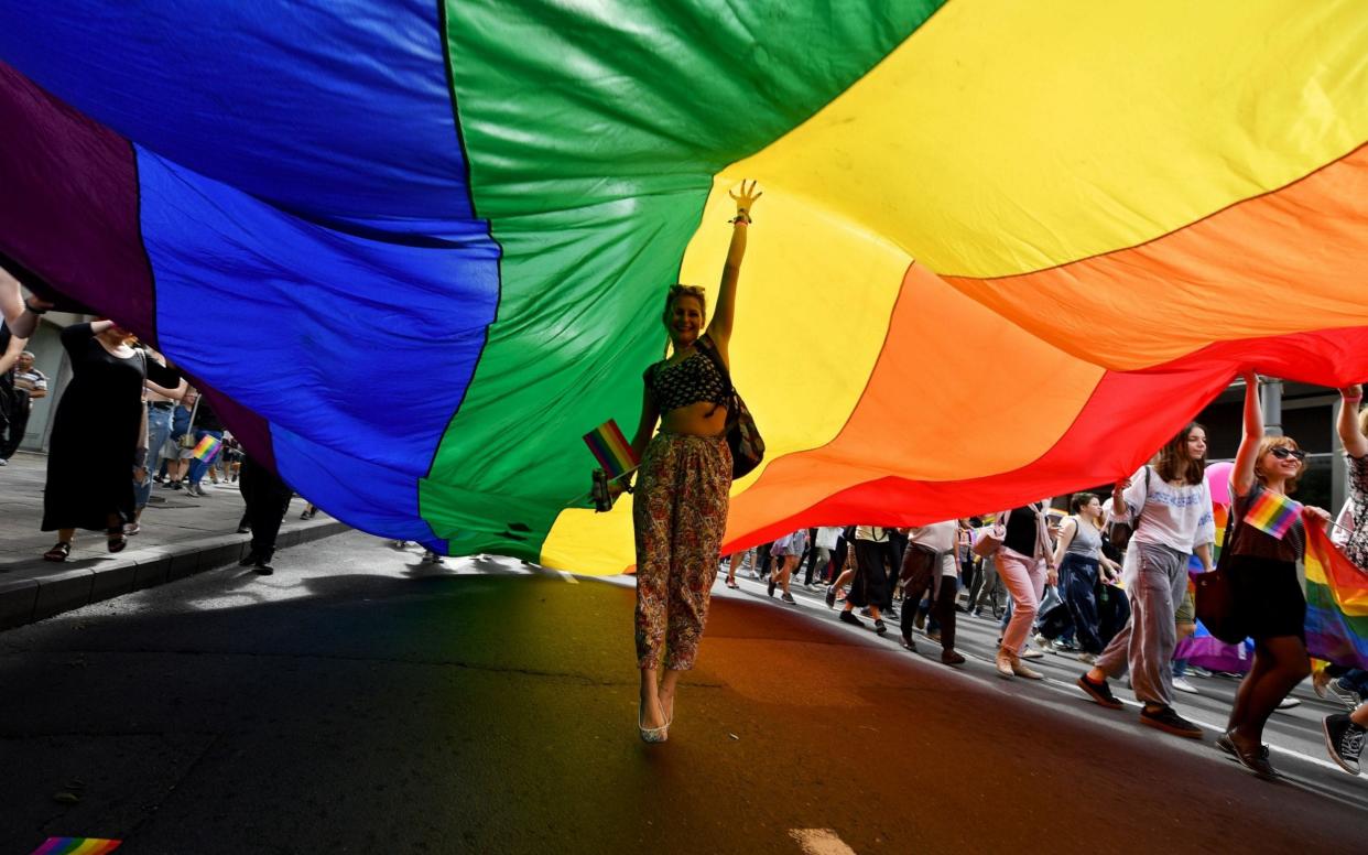 A woman dances under a huge rainbow flag during the Gay Pride parade on September 17, 2017 in Belgrade. Serbia - AFP