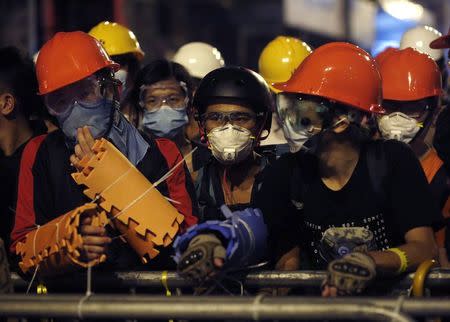 Pro-democracy protesters protect themselves with helmets, masks and foam pads during a standoff with riot police at the Mongkok shopping district in Hong Kong early October 19, 2014. REUTERS/Bobby Yip